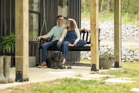 Couple sitting on a porch swing with a dog at their feet.